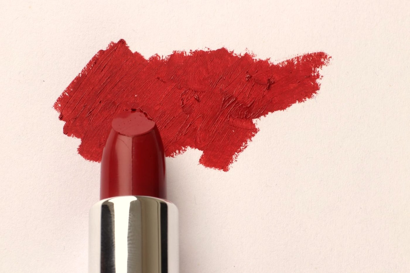 Deep red beauty products styled on a dark surface