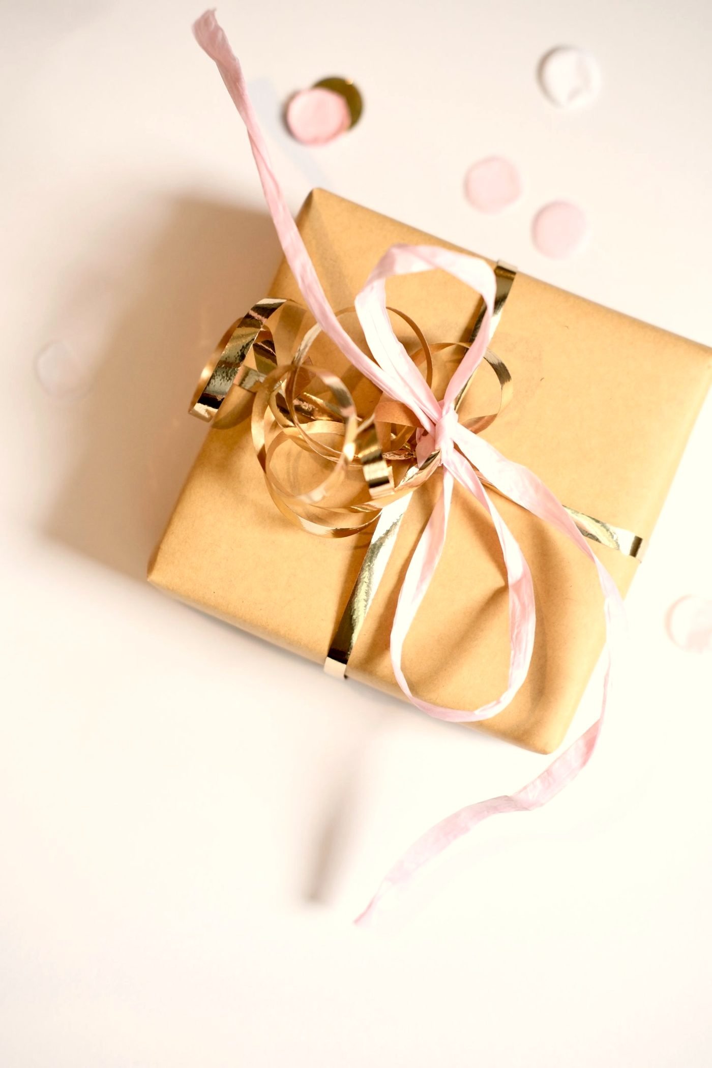 A wrapped gift with a burgundy ribbon on a warm surface