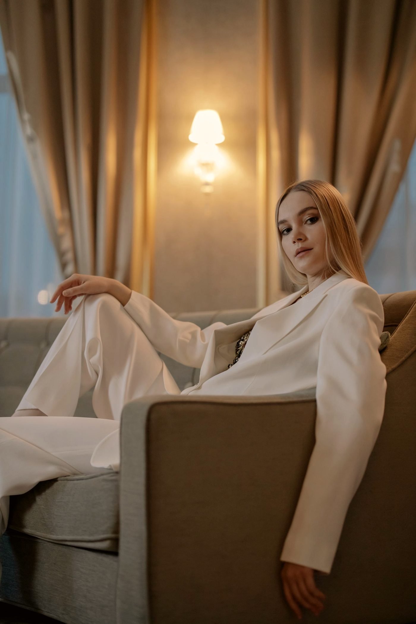 A woman in a tailored white suit standing in a warm room