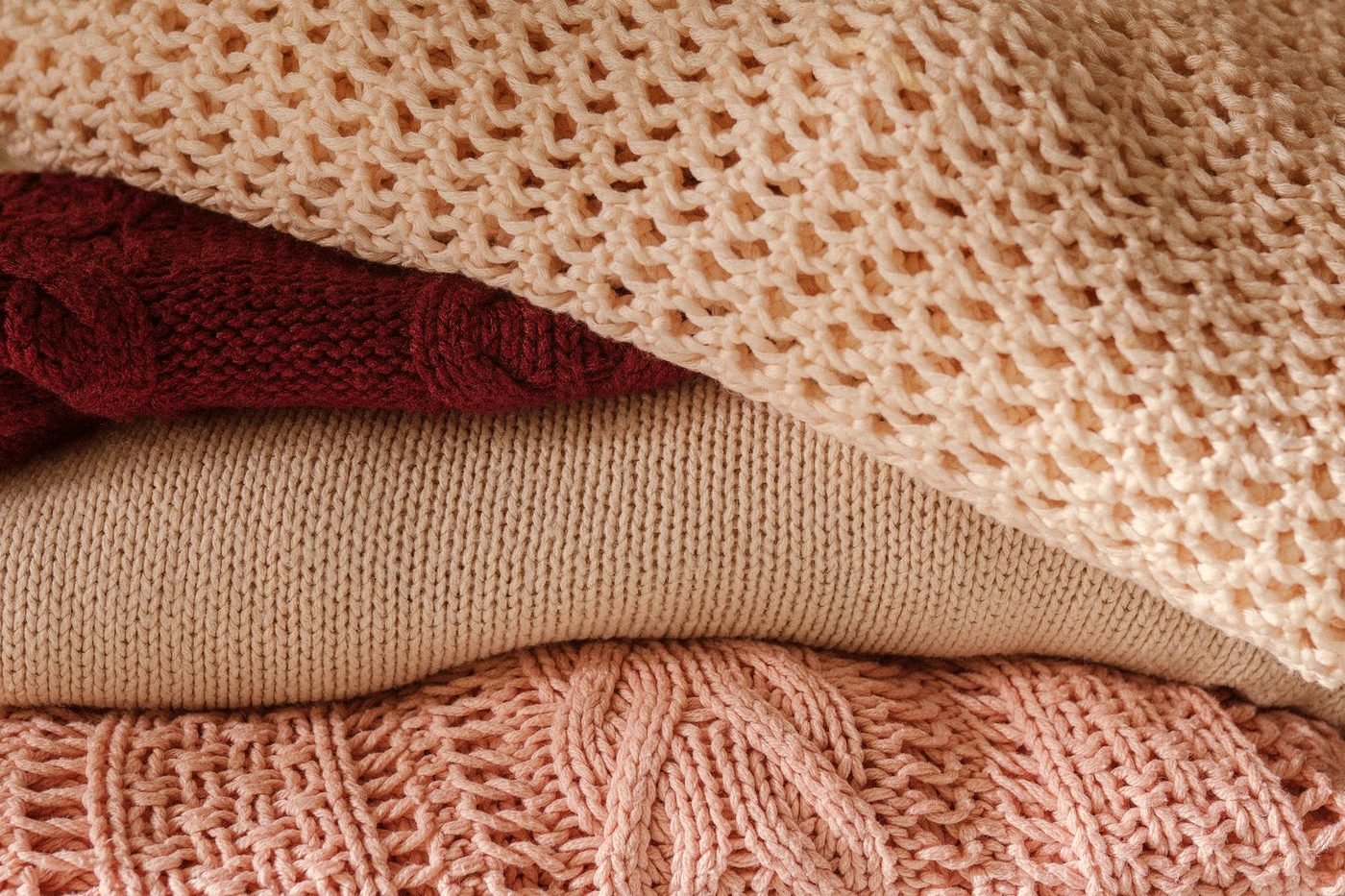 Folded knitwear stacked in cream and burgundy